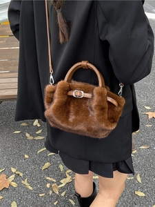Elegante braune Kunstfelltasche mit Lederriemen und Metallschnalle in herbstlicher Kulisse