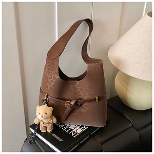 Detail of leopard print shoulder bag with decorative belt and brown plush bear charm
