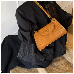 Detail of a brown leather shoulder bag with pleated texture and gold chain strap