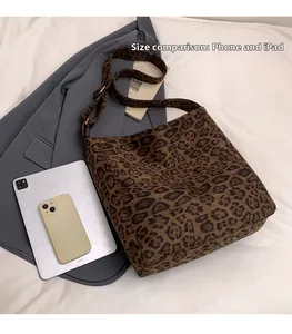 Size comparison of large leopard print tote bag next to an iPad and smartphone