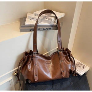 Detailed close-up of brown vintage PU leather shoulder bag with drawstring and metal rings