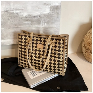 Detail of checkered tote bag with leather logo patch and sturdy canvas shoulder straps