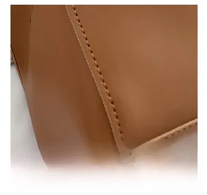 Macro detail of high-quality stitching and grainy leather texture on a brown tote bag