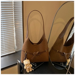 Close-up of caramel brown suede Hobo shoulder bag with buckle strap and bear charm