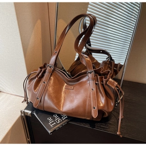 Détail du sac bandoulière en cuir caramel avec cordon de serrage et œillets métalliques