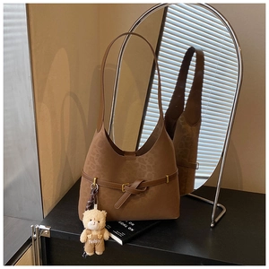 Detail of leopard print suede bucket bag with decorative belt and cute bear charm