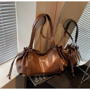 Détail d'un sac cabas en cuir marron avec fermeture à cordon et bandoulière à œillets