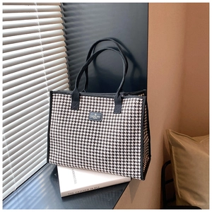 Detail of houndstooth canvas tote bag with black straps and square message patch