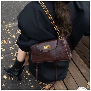 Detail showing the coffee brown wrinkled oil wax leather and gold chain of the handbag