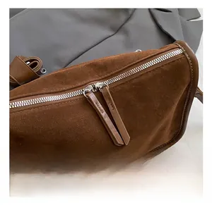 Detail der braunen Wildleder-Tasche mit hochwertigem silbernem Doppelreißverschluss und Leder