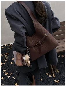 Detailed shot of leopard print shoulder bag with decorative buckle and plush bear charm