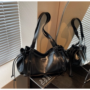 Détail du sac en cuir noir brillant avec fermeture à cordon et bandoulière à œillets