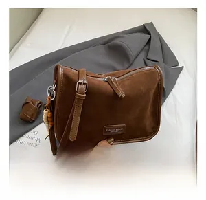 Nahaufnahme der braunen Wildledertasche mit Doppelreißverschluss und Holzperlen-Detail