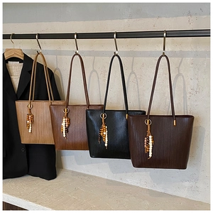 Dettaglio di quattro borse tote in pelle intrecciata marrone e nero con ciondoli