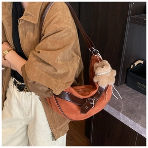 Detailopname van vintage bruine suède hobo tas met lederen riemen en beer bedeltje