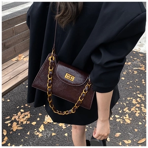 Close-up of vintage deep brown embossed leather underarm bag with gold chain and metal lock