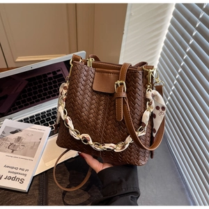 Detail of hand-woven dark brown bucket bag with decorative chain and silk scarf wrap