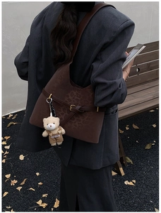 Detail of leopard print tote bag with plush bear charm worn by a model in autumn