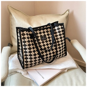 Detail of checkered tote bag with leather label resting on a chic beige chair