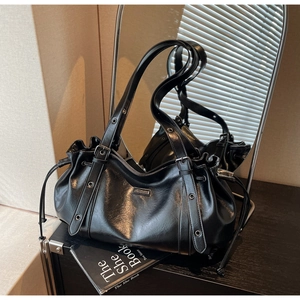 Détail de la texture en cuir PU mat noir et de la plaque logo en métal sur le sac à bandoulière