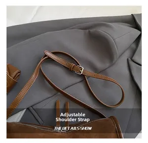 Detailaufnahme des verstellbaren braunen Ledergurts mit silberner Schnalle an der Tasche