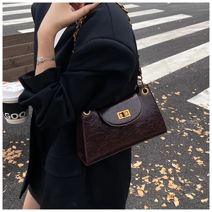 Close-up of a burgundy pleated leather crossbody bag with gold chain and turn-lock