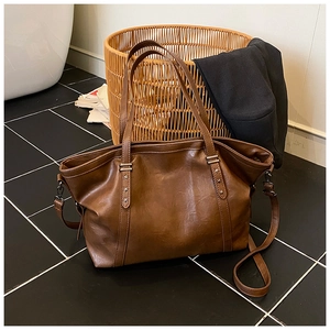 Détail du sac cabas en cuir marron foncé avec rivets étoiles argentés et bandoulière