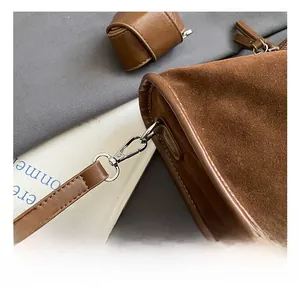 Detailansicht des Metallhakens und der Ledernaht an einer braunen Wildleder-Schultertasche