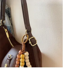 Détail du sac en daim marron avec bandoulière réglable et pendentif en perles de bois