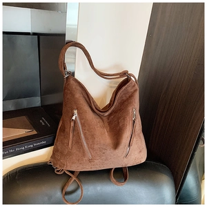 Détail du sac à bandoulière en daim marron foncé avec fermetures éclair vintage et texture douce