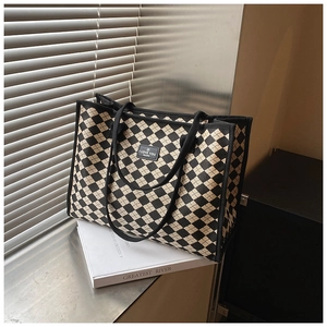 Detailed close-up of checkered canvas tote bag with woven texture and branded leather label