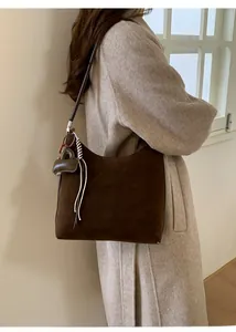Detail view of dark brown suede hobo tote bag with stylish heart and tassel charms