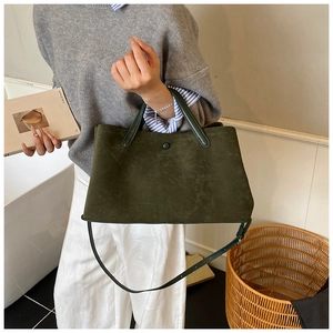 Close-up of deep green matte suede tote bag with leather handles and button closure detail