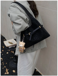 Detail of black leopard embossed shoulder bag with a cute teddy bear fashion charm