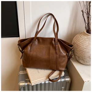 Détail d'un grand sac cabas marron en similicuir avec rivets en étoile et bandoulière