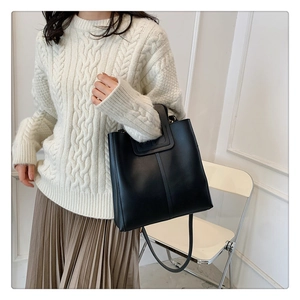 Detail of minimalist black tote bag with vertical stitching and detachable shoulder strap