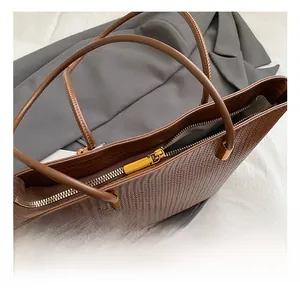 Dettaglio della borsa tote intrecciata marrone scuro con cerniera dorata e fodera interna