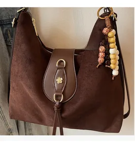 Détail du sac cabas marron mat avec boucle fleur dorée et pendentif à perles