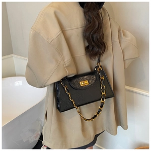 Detail of a black patent leather chain bag showing glossy wrinkled texture and gold buckle