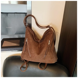 Détail d'un sac cabas en daim marron avec fermetures éclair sur fauteuil en cuir