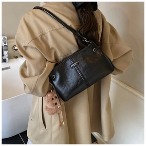 Détail du sac à main noir brillant en PU avec logo en métal et breloque ours brun