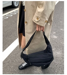 Modern black nylon crescent bag shown worn by a model in a casual outdoor setting