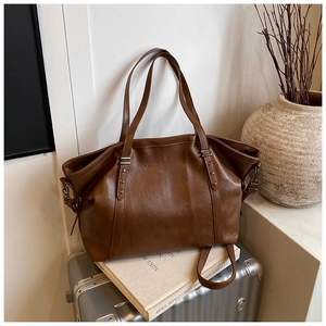 Détail du sac cabas marron vintage avec rivets en étoile sur une valise