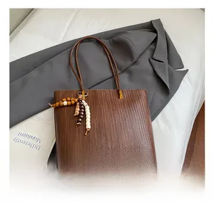Dettaglio della borsa tote marrone a trama intrecciata con nappa in perline di legno