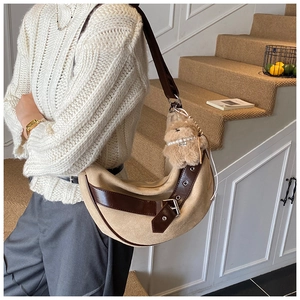 Detail of hobo bag with leopard vibes, beige suede texture and brown plush bear charm