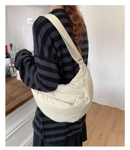 Close-up of cream quilted crescent bag showing the soft nylon texture and wide strap