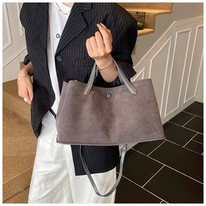 Detail of grey suede tote bag featuring reinforced handles and adjustable shoulder strap