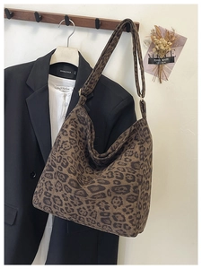 Detail of leopard print tote bag with adjustable metal buckle on a dark suit background