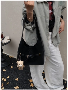 Detail of black faux leather shoulder bag with gold metal buckle and cute bear pendant