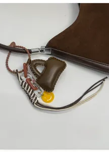 Detail of dark brown suede tote with decorative mini-bag pendant and acrylic chains